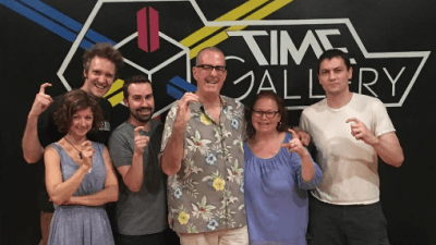 Escape Room Team Poses In Front Of Time Gallery Logo