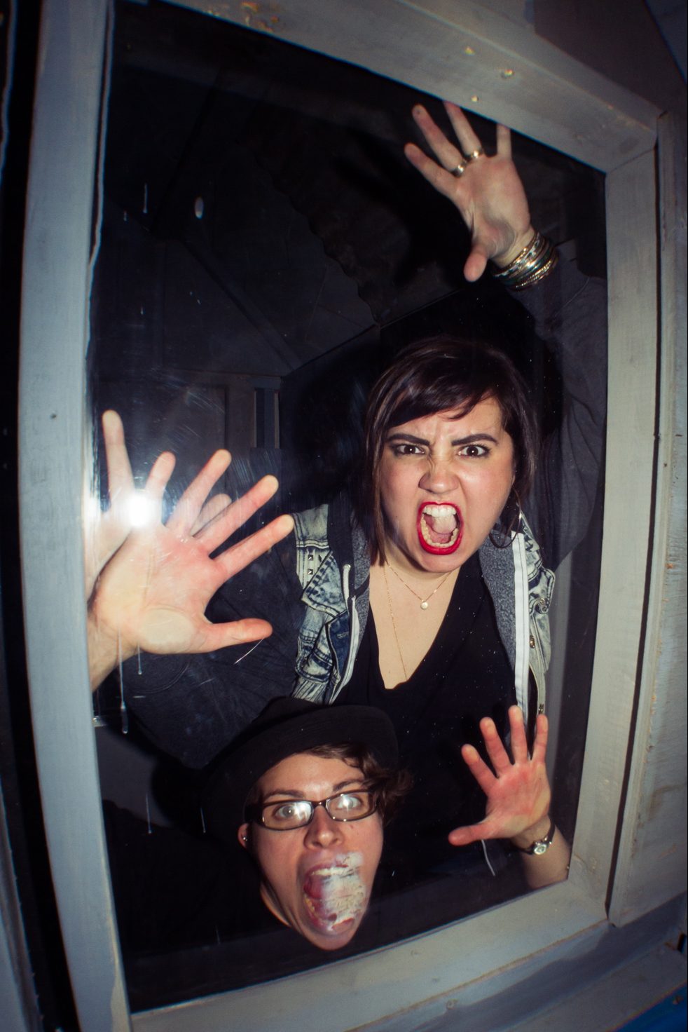 Two People With Yelling Faces Pressed Against A Window